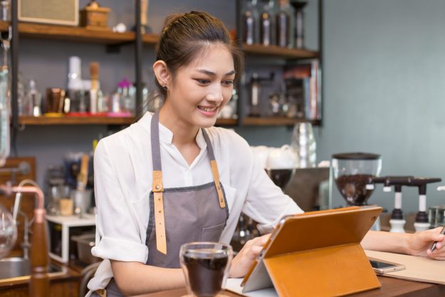 Asian barista woman using tablet for promote shop. Woman using t